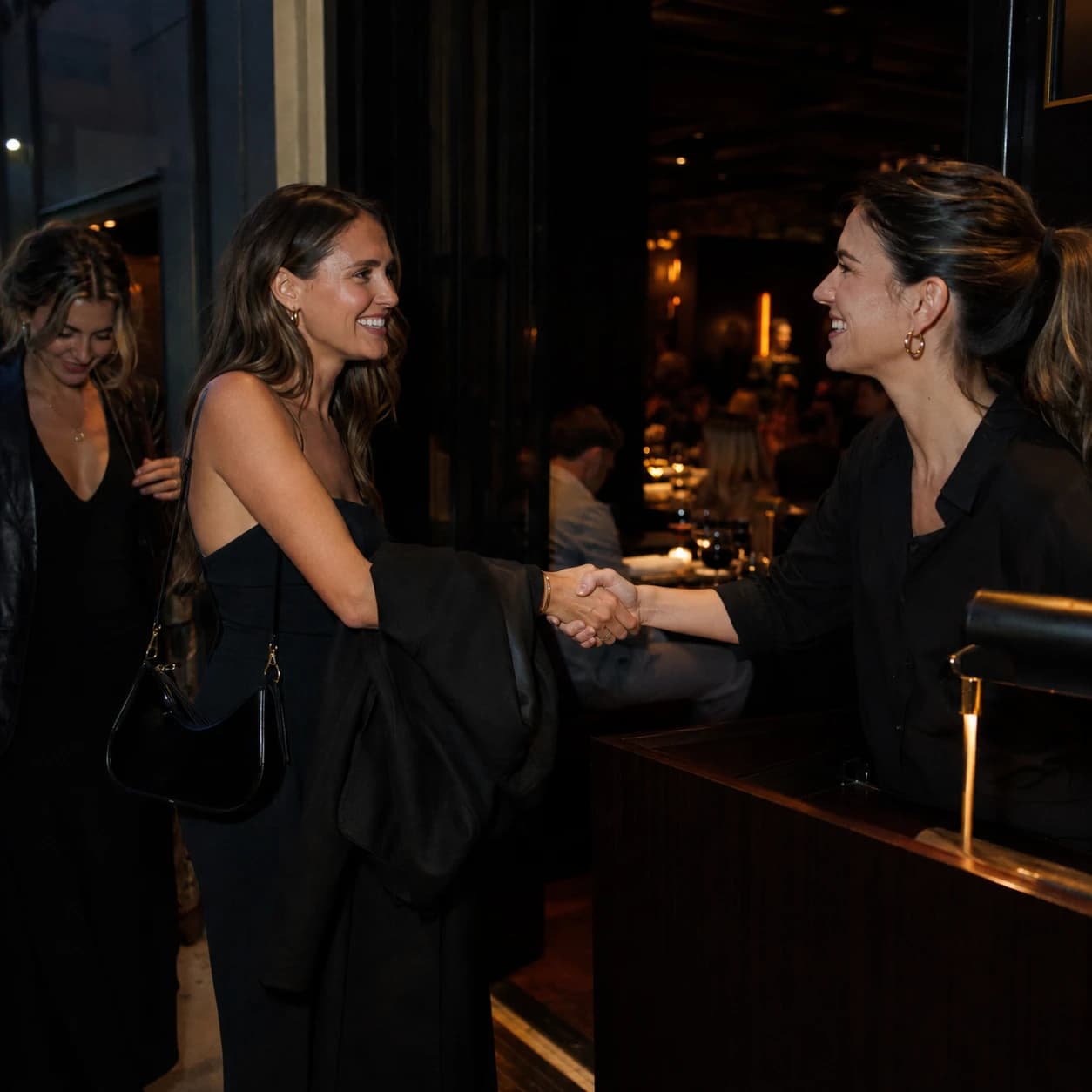 A host shaking hands with an arriving guest across the host stand